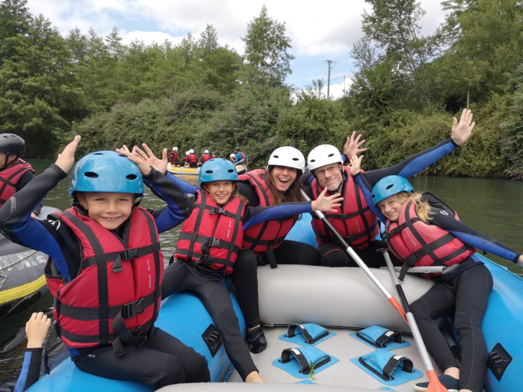 Une famille souriante lors d'une descente en rafting sur le gave de Pau.